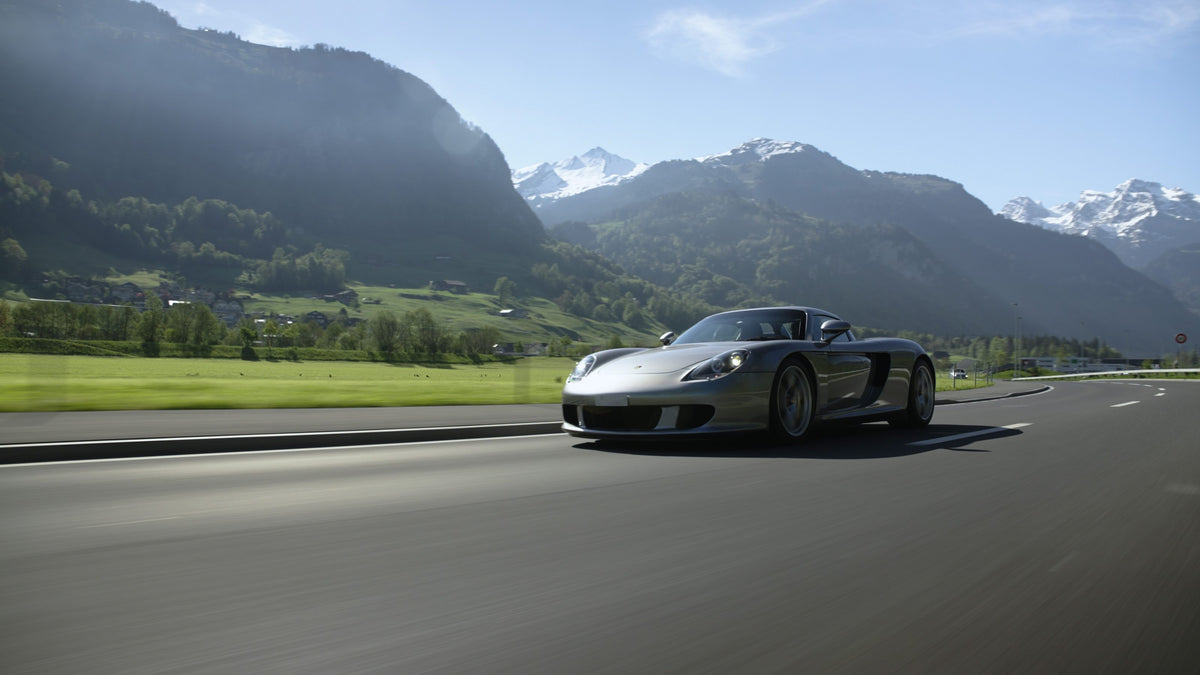 Porsche Carrera GT auf einer Landstraße vor Bergkulisse